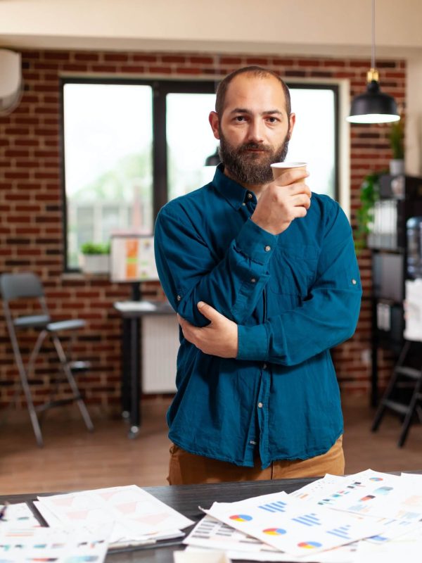 portrait-of-bookkeeper-man-holding-cup-of-coffee-standing-in-startup-company-office.jpg